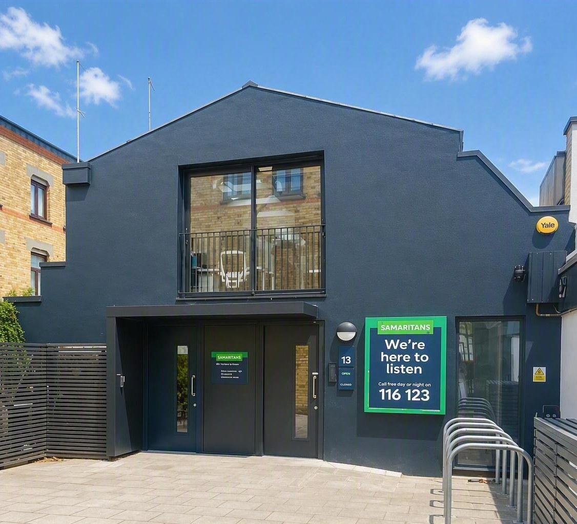 The Central London Samaritans branch, a dark grey building with a sign reading We&rsquo;re here to listen and the free number 116 123
